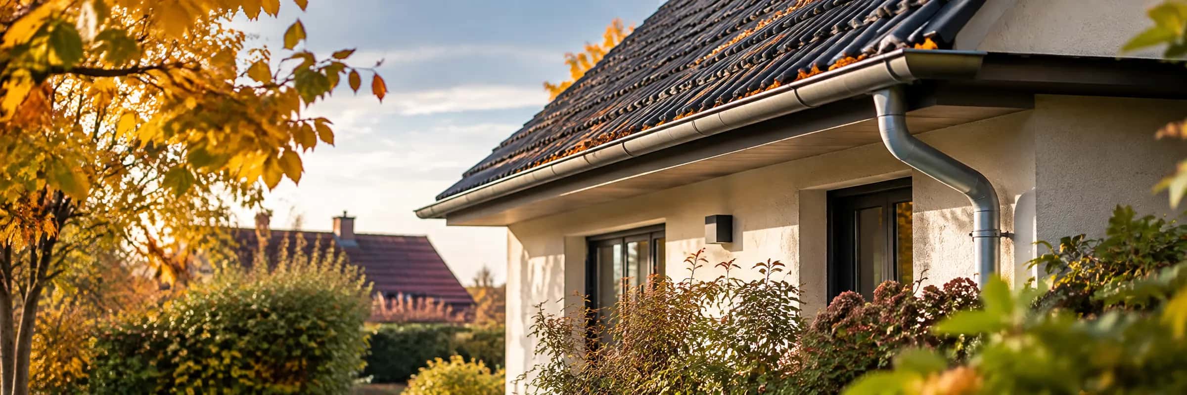 Maison aux tuiles rousses entourée de feuillages d’automne