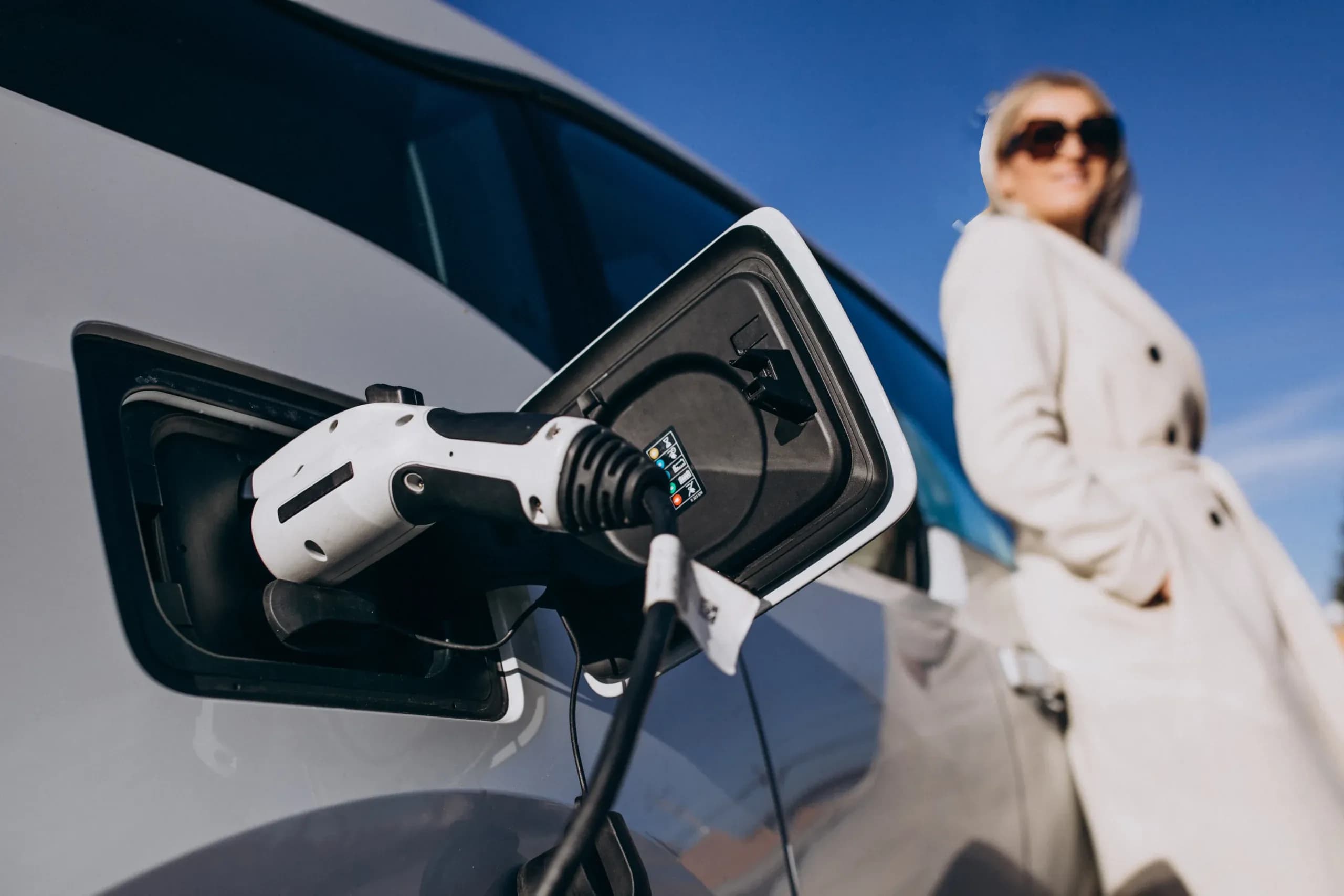 Câble de recharge branché sur la prise d’une voiture électrique blanche